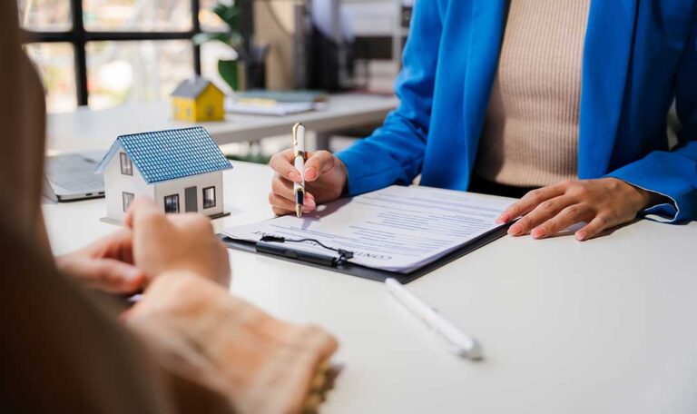 A homeowner reviews renovation blueprints and insurance documents together at a kitchen table.