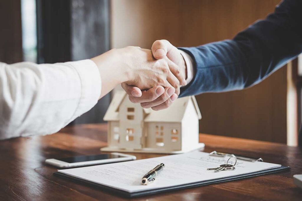 A couple reviews insurance papers beside a home inventory folder and smartphone photos of household belongings.